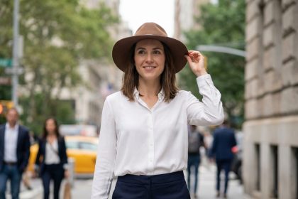 Femme élégante ajustant son chapeau dans la ville