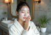 Skincare coréenne : tout savoir sur cette pratique de soin de la peau ! Jeune femme asiatique appliquant un masque facial dans sa salle de bain