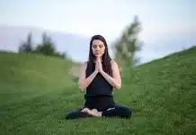 woman in black tank top and black pants sitting on green grass field during daytime