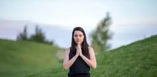 woman in black tank top and black pants sitting on green grass field during daytime